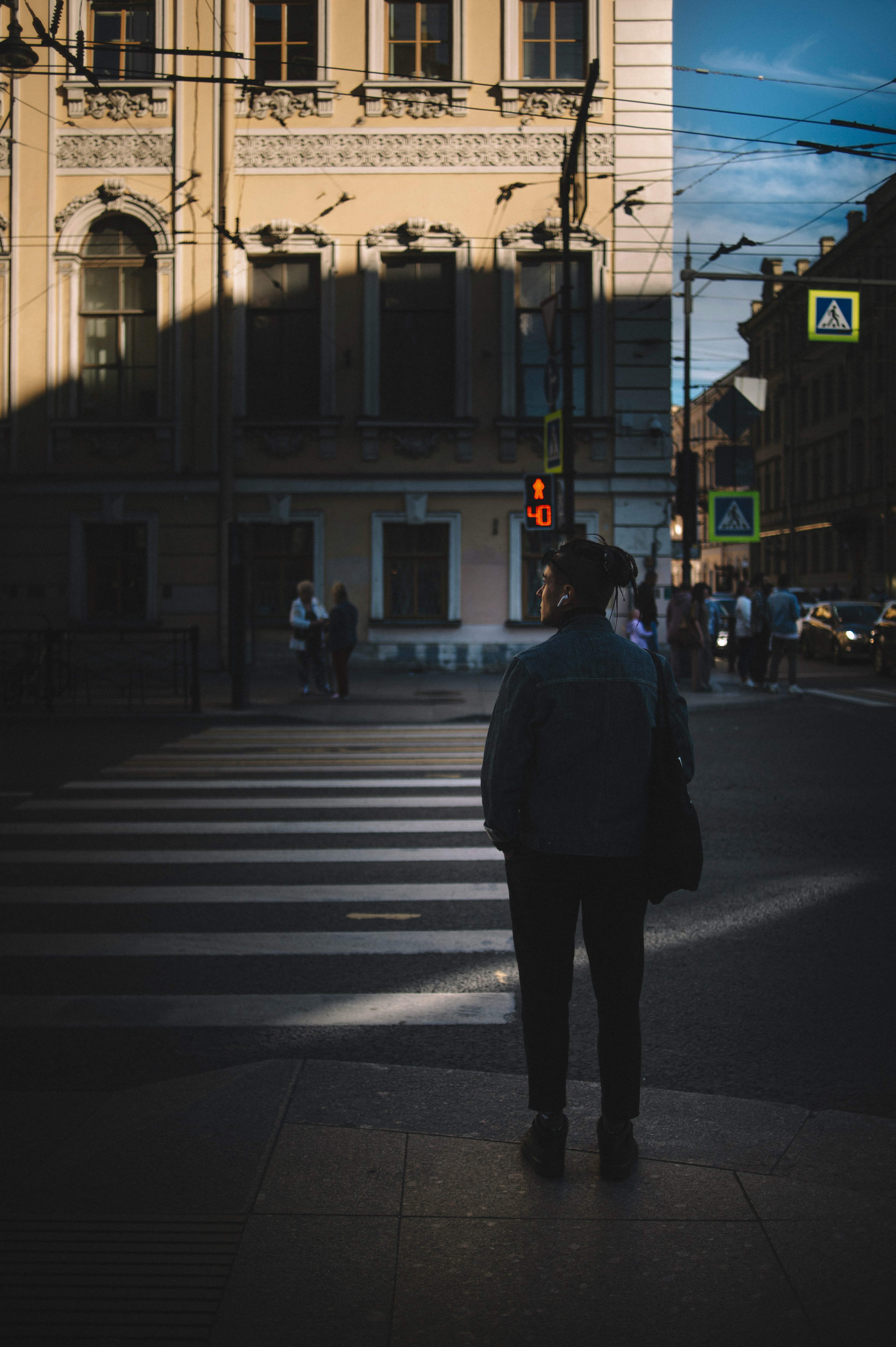 man in white jacket and black pants standing on pedestrian lane during daytime